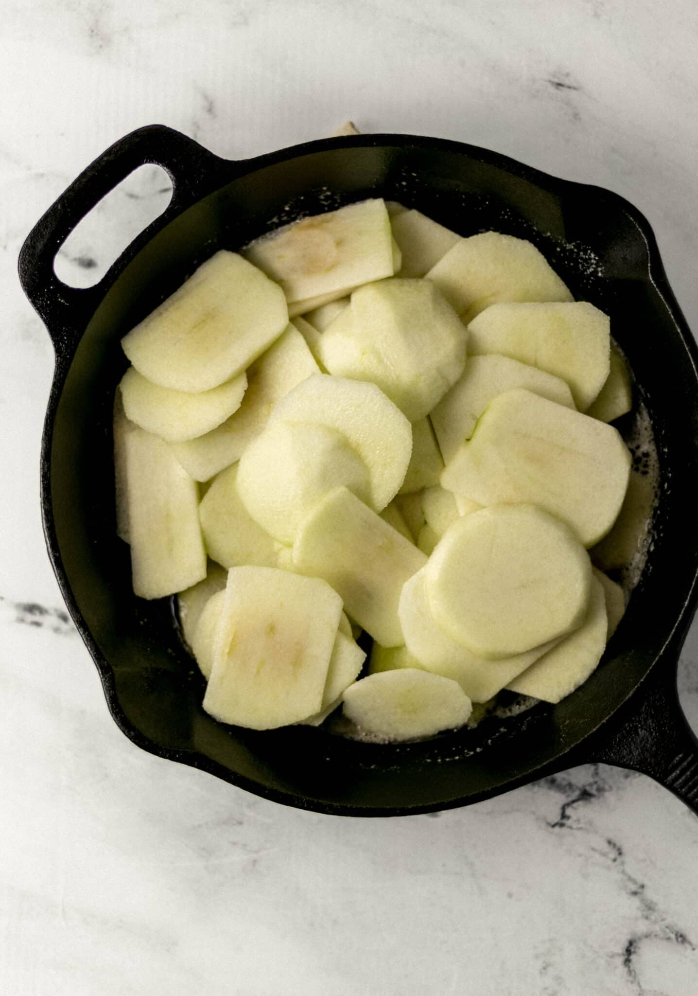 apple slices and lemon juice added to cast iron skillet 