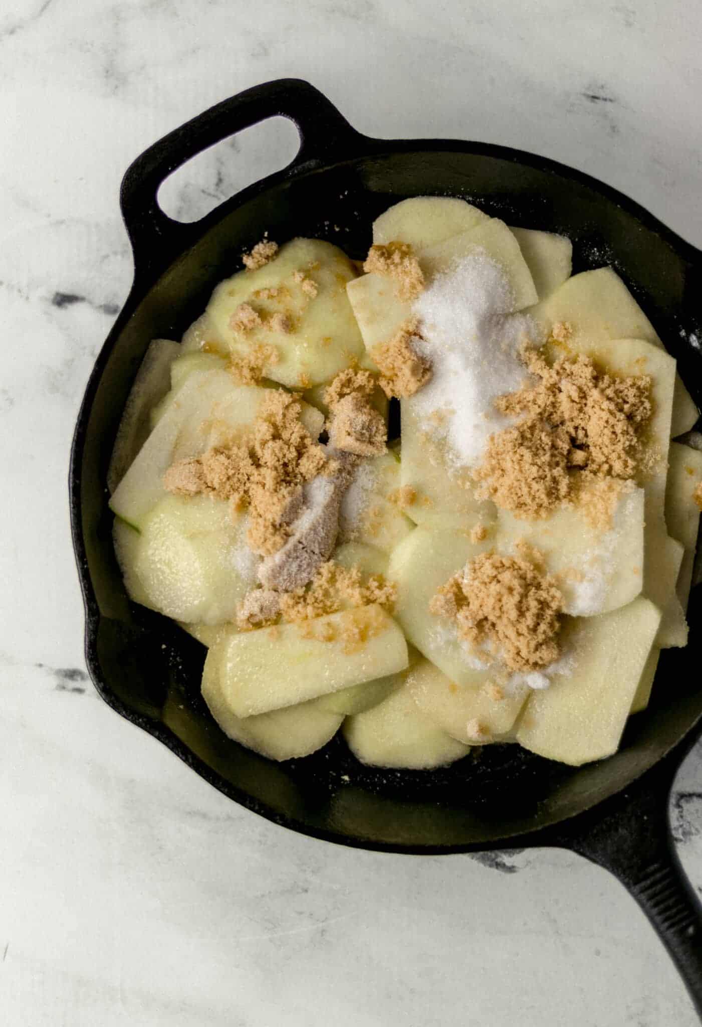 granulated sugar and brown sugar added to skillet with apples