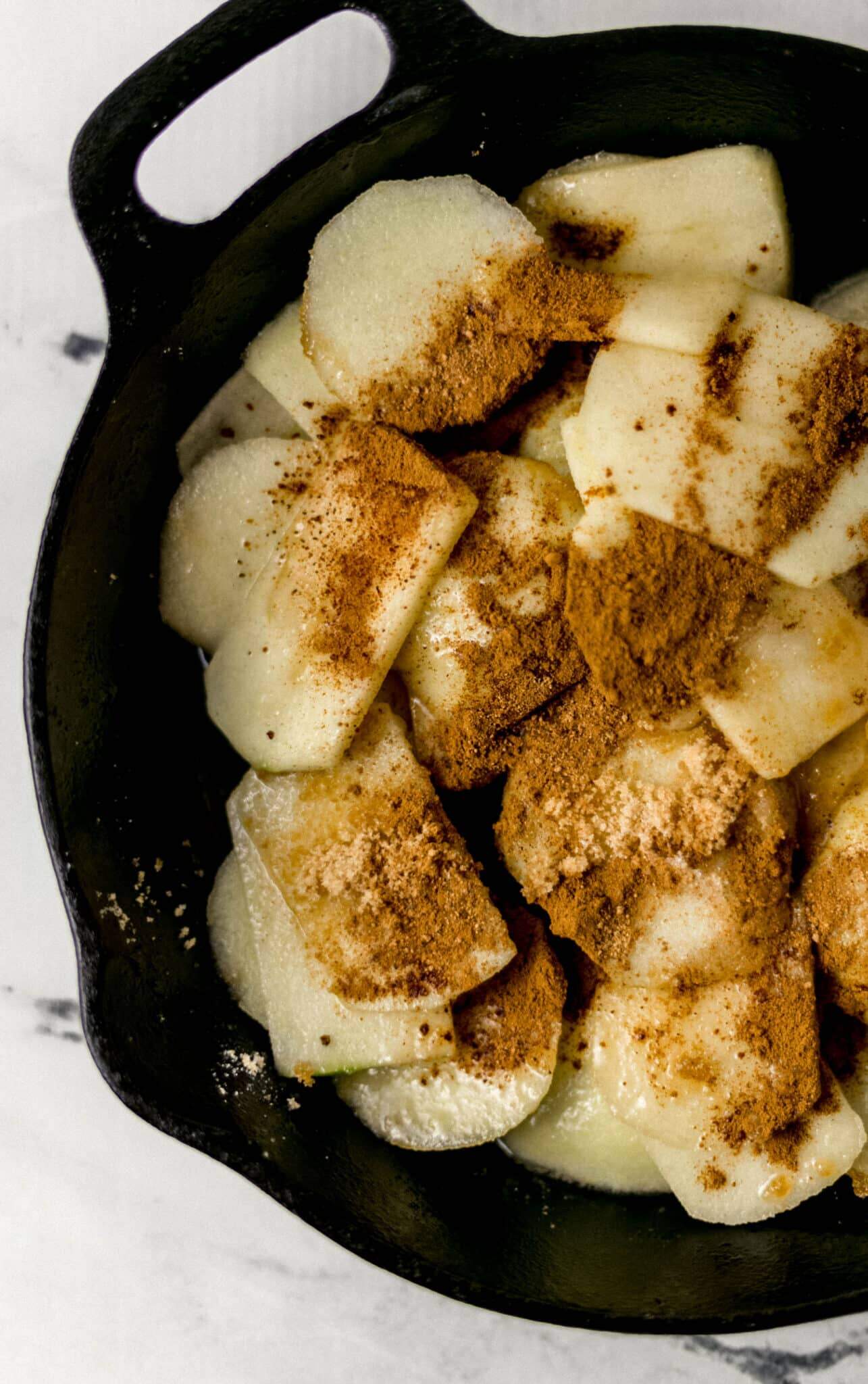 cinnamon and nutmeg added to skillet with apples and sugar