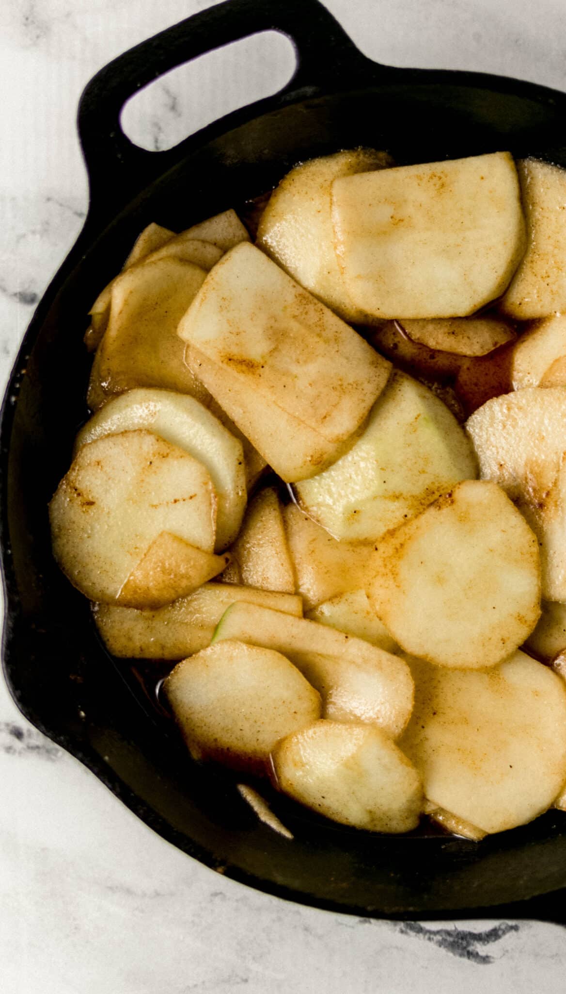 finished fried apples in cast iron skillet on marble surface 