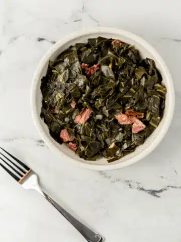 overhead view of finished white bowl of southern collard greens recipe with ham hocks