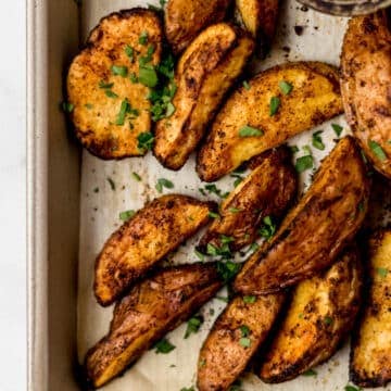 overhead view of baked potatoes on parchment lined baking sheet