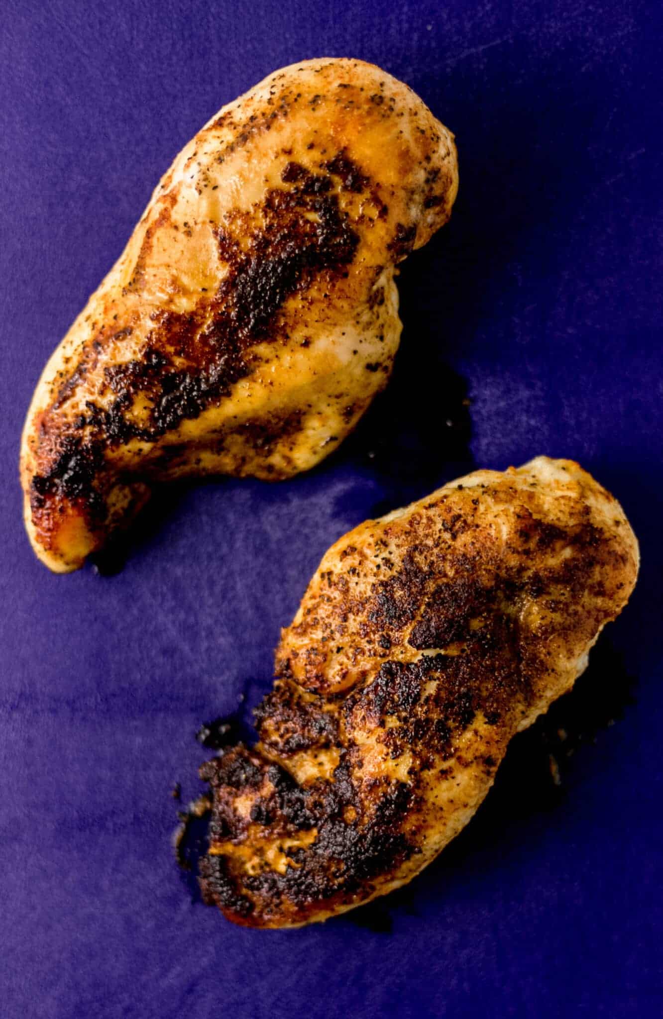 cooked chicken breast resting on blue cutting board 