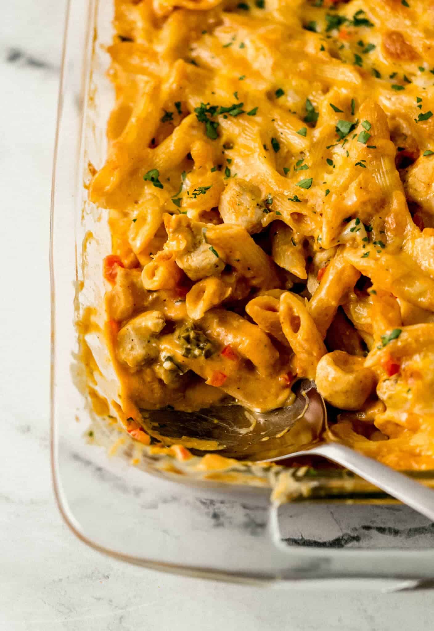 baked pasta in glass baking dish with a serving spoon in it 