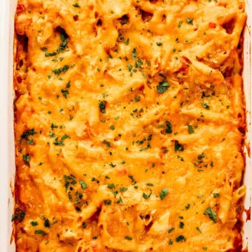 Overhead view of casserole dish with finished enchilada past in it topped with chopped parsley.
