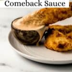 Close up side view of chicken being dipped in sauce on plate on pin with text overlay.