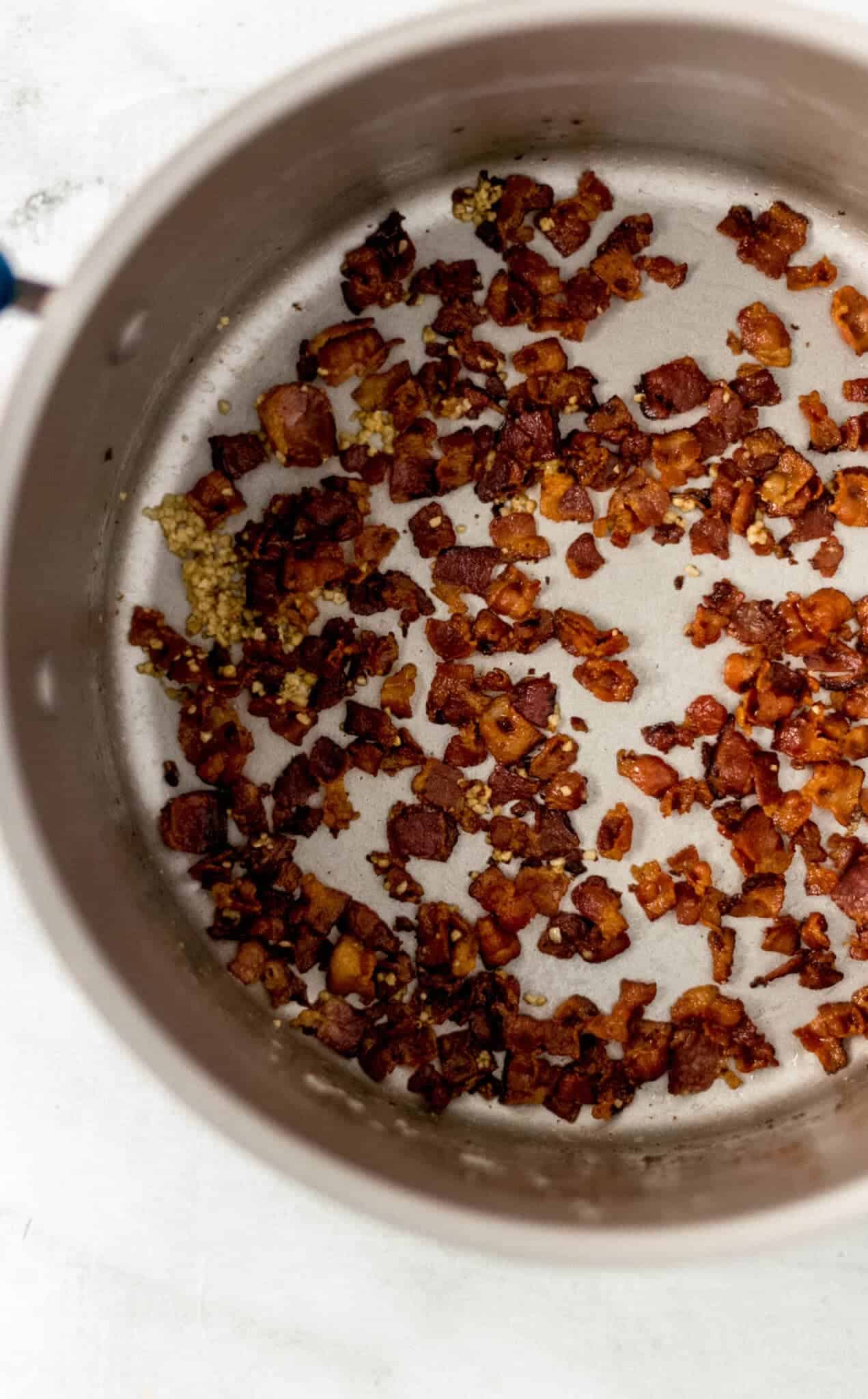 overhead view of cooked bacon and garlic in pot