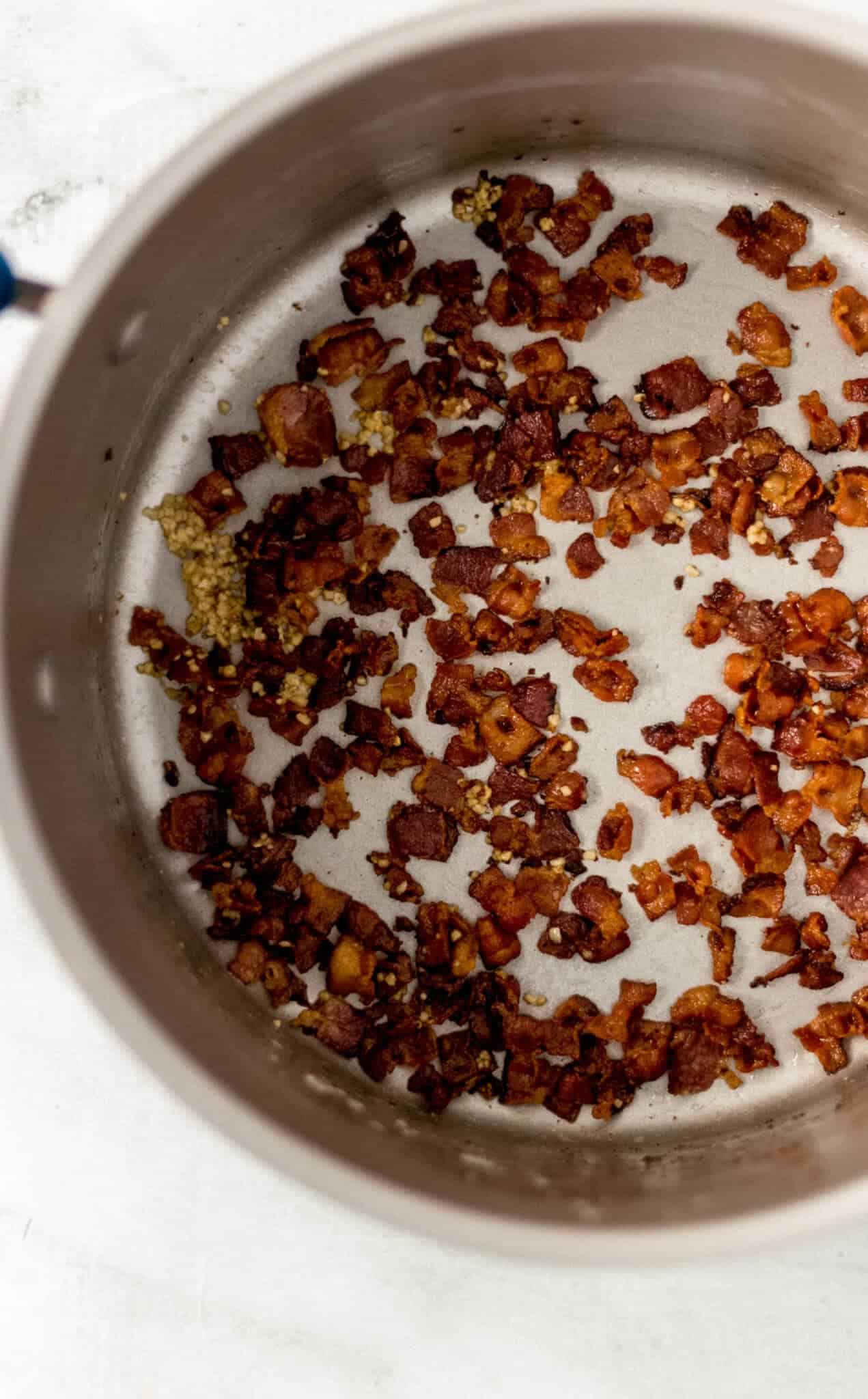 overhead view of cooked bacon and garlic in pot 