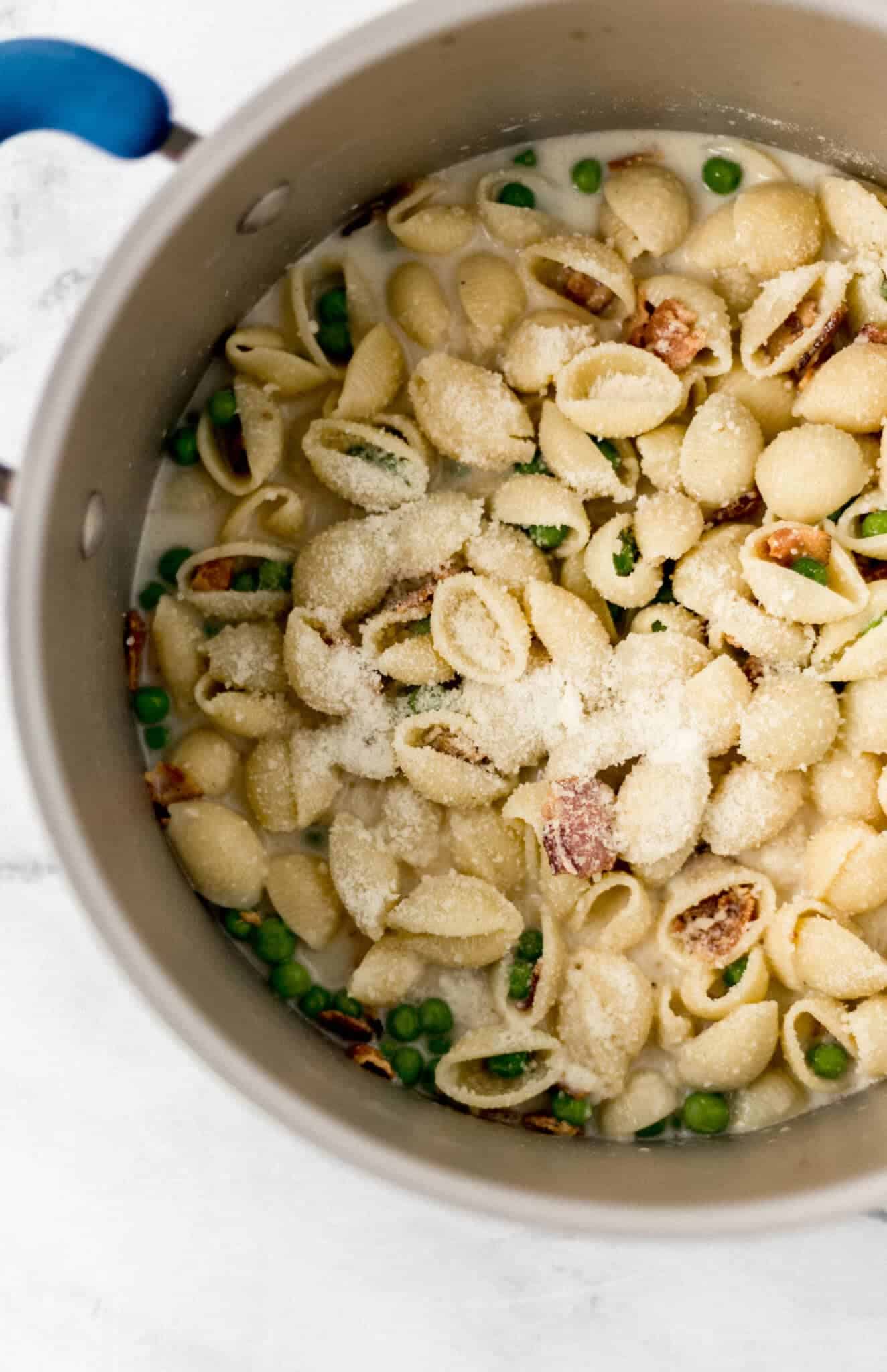 finished pasta in pot topped with grated parmesan cheese