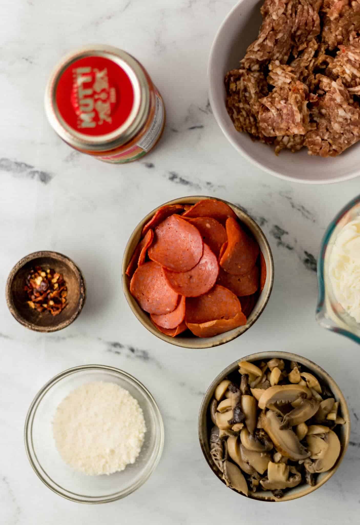 overhead view of ingredients needed to make pizza bowls in separate bowls