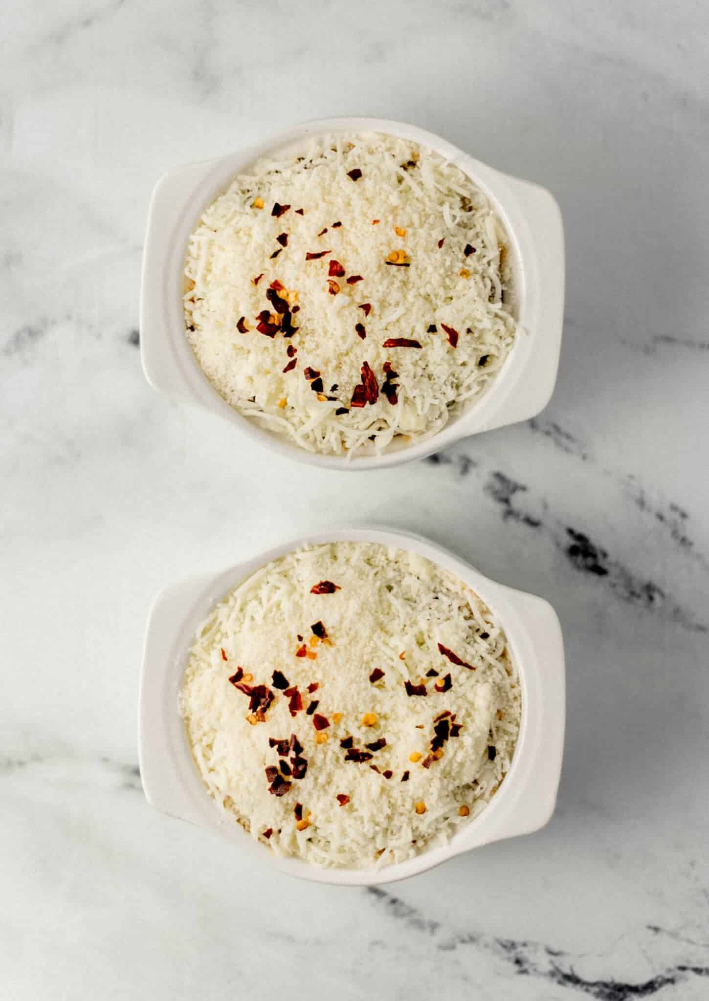 assembled pizza bowls in two white ramekins before baking