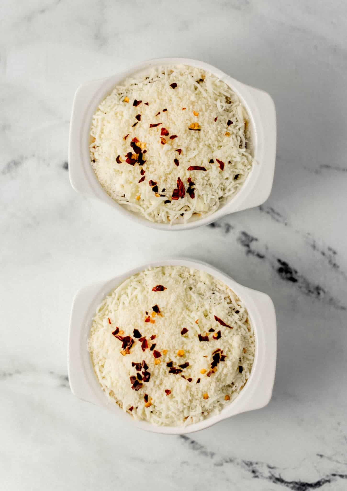 assembled pizza bowls in two white ramekins before baking 