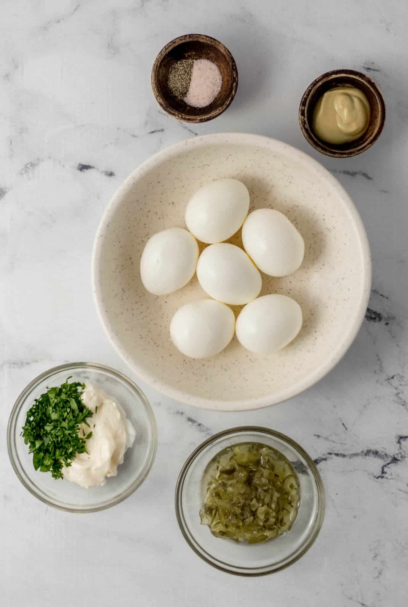 overhead view of ingredients needed to make egg salad in separate bowls