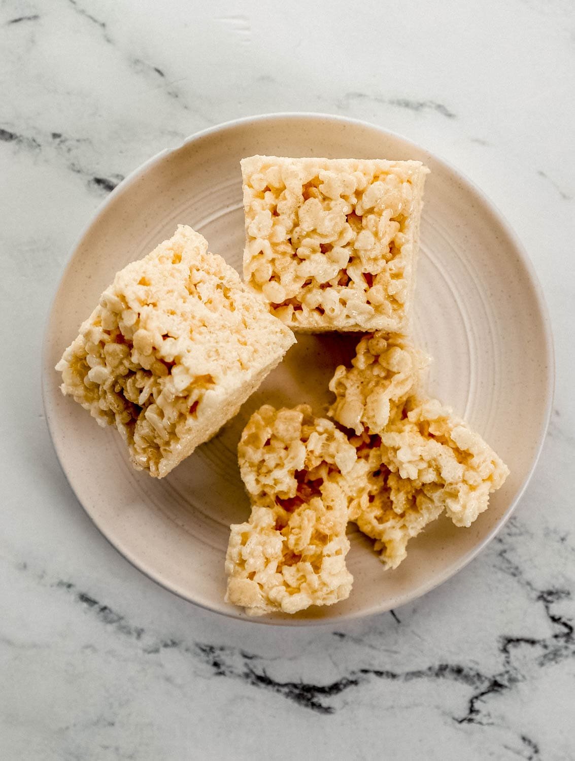 Overhead view of three finished treats on white plate on marble surface.