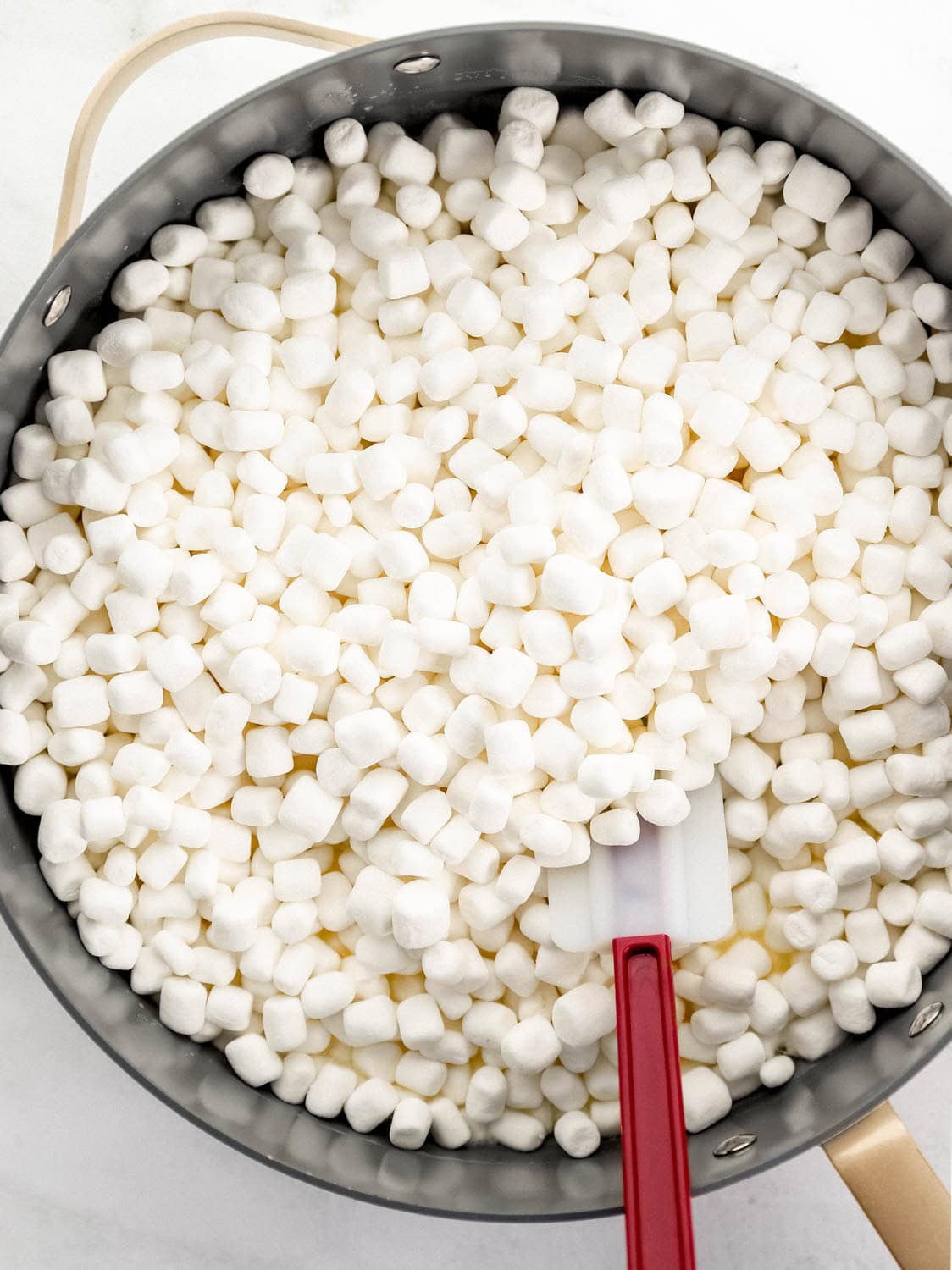 Mini marshmallows and melted butter in large pot with spatula.