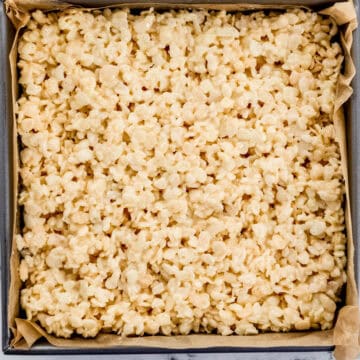 Overhead view of rice krispie treats in parchment lined square baking sheet.