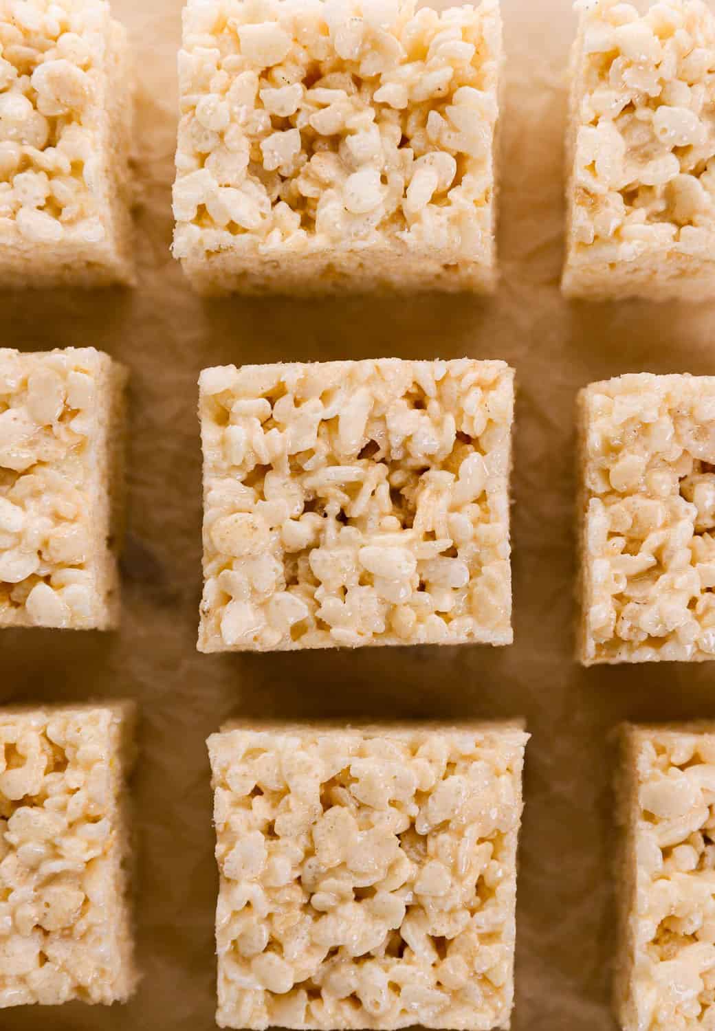 Overhead view of finished rice krispie treat squares on parchment paper.