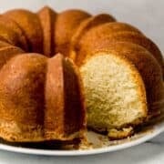 Close up side view of cake on a white plate with slices taken out of it.