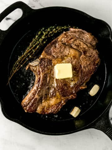steak in cast iron skillet topped with butter