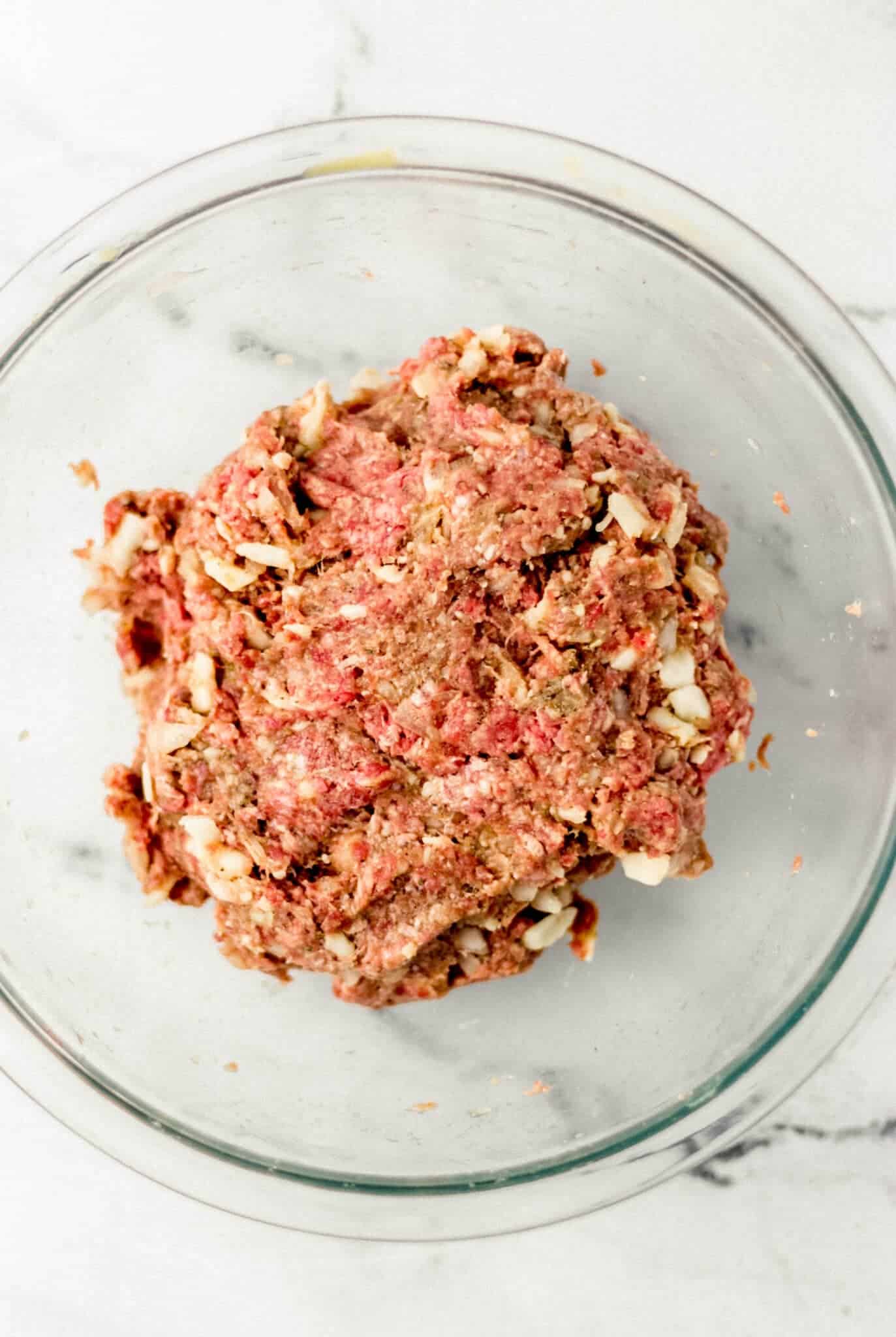 meatball ingredients combined in glass mixing bowl 