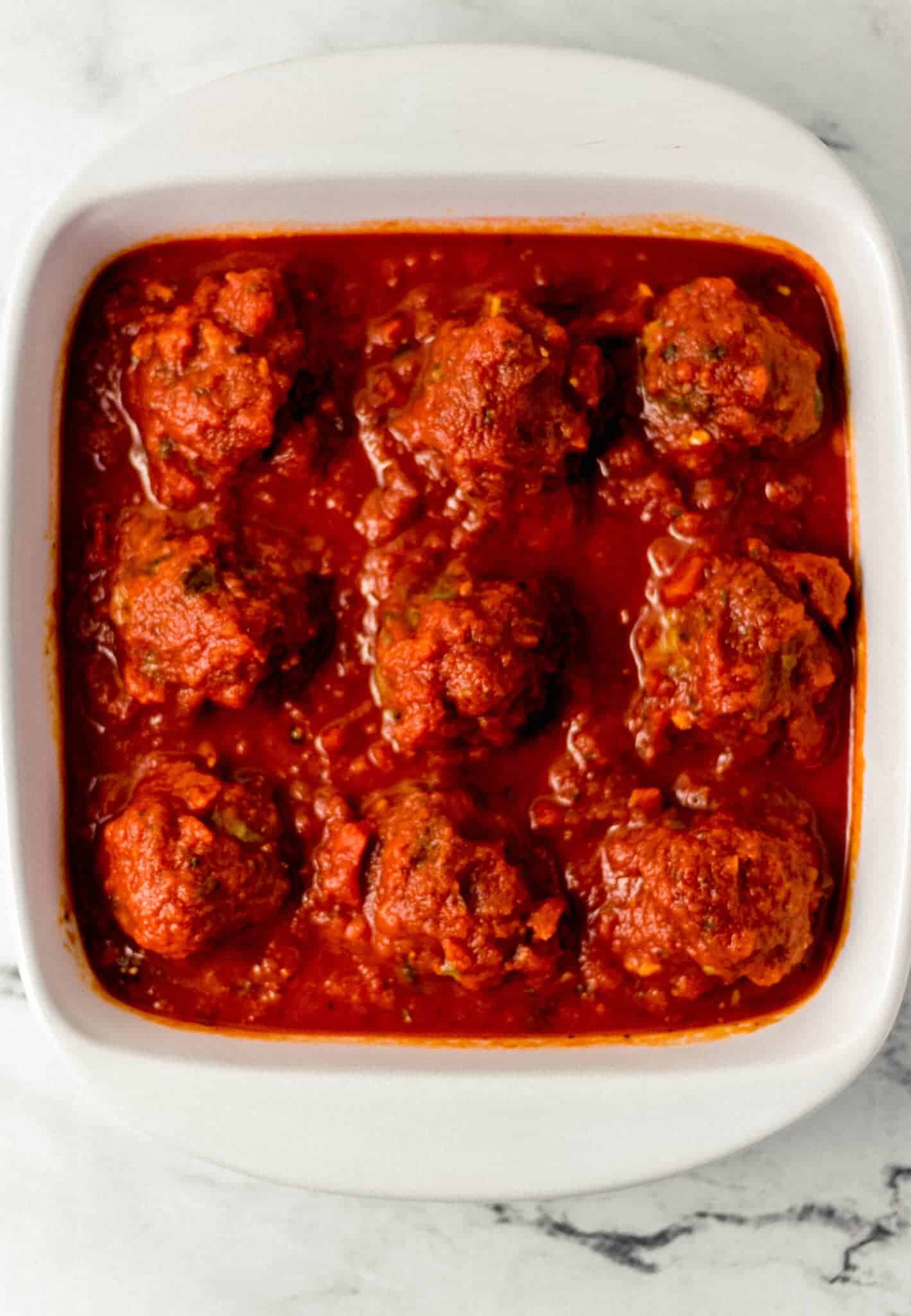 meatballs topped with sauce in white baking dish 