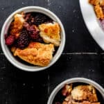 Overhead view of cobbler in two white bowls on black tile surface.