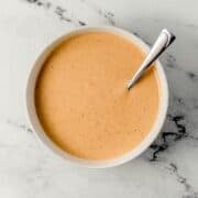 Overhead view of sauce in a white bowl with spoon.
