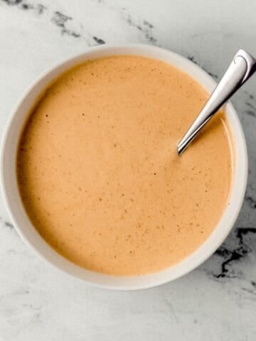 Overhead view of sauce in a white bowl with spoon.