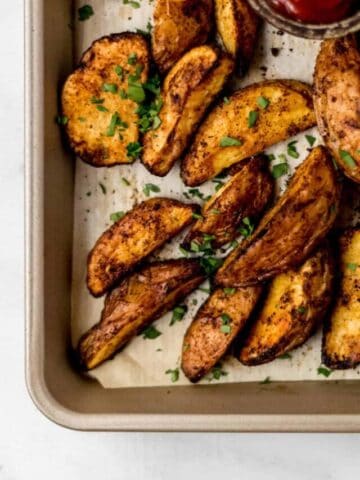 overhead view of baked potatoes on parchment lined baking sheet