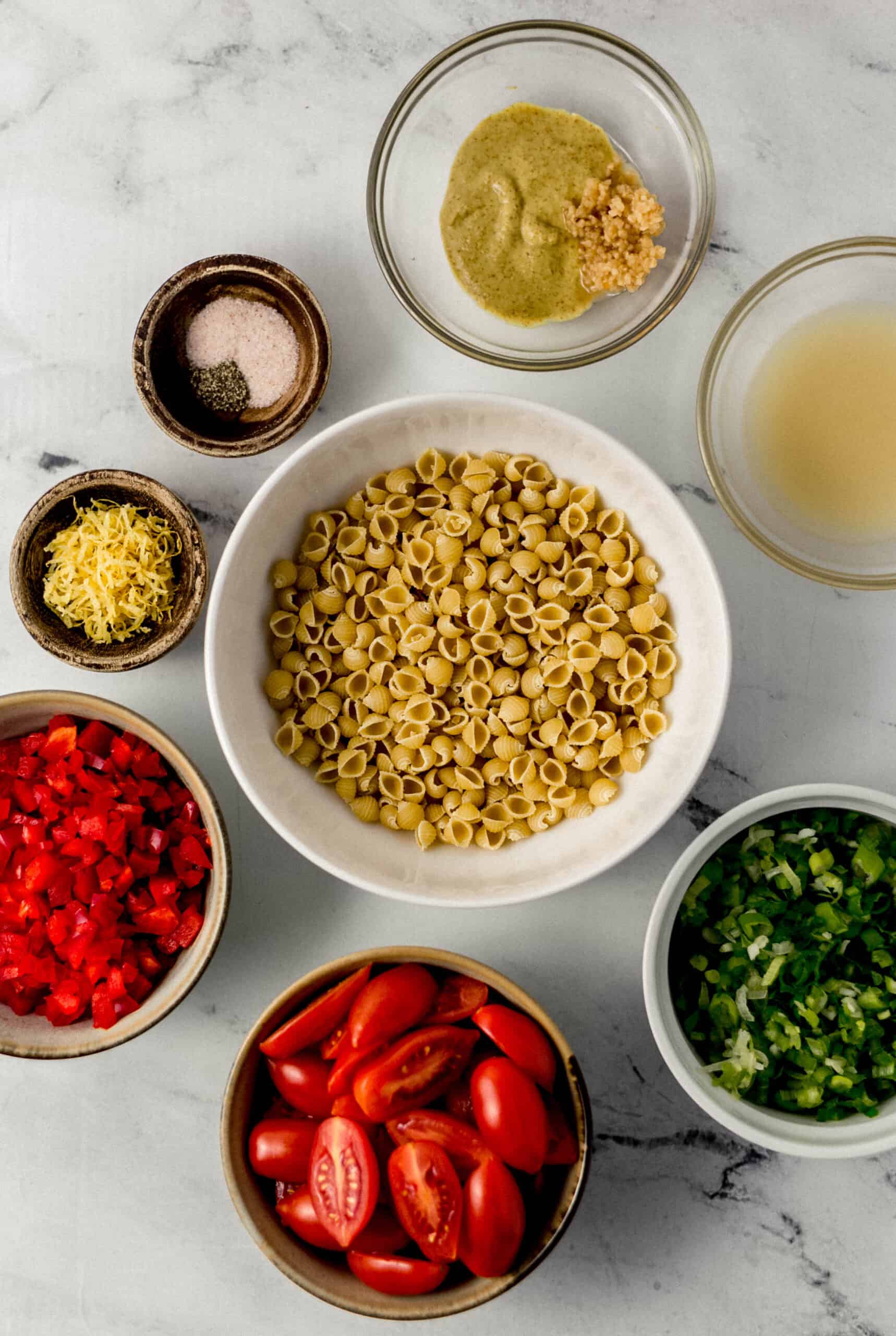 overhead view of ingredients needed to make pasta salad in separate bowls 