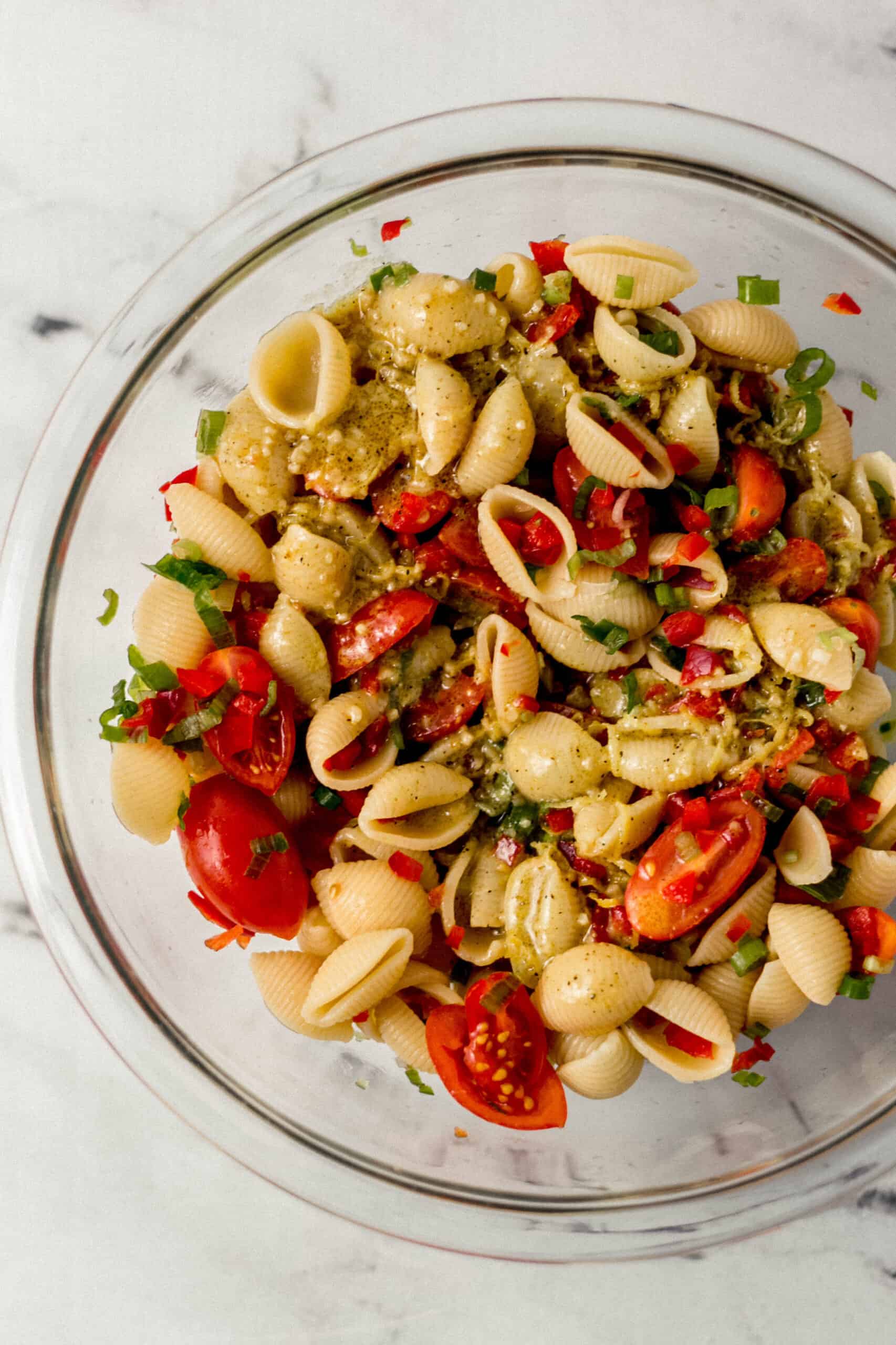 pasta salad topped with dressing in large glass mixing bowl 