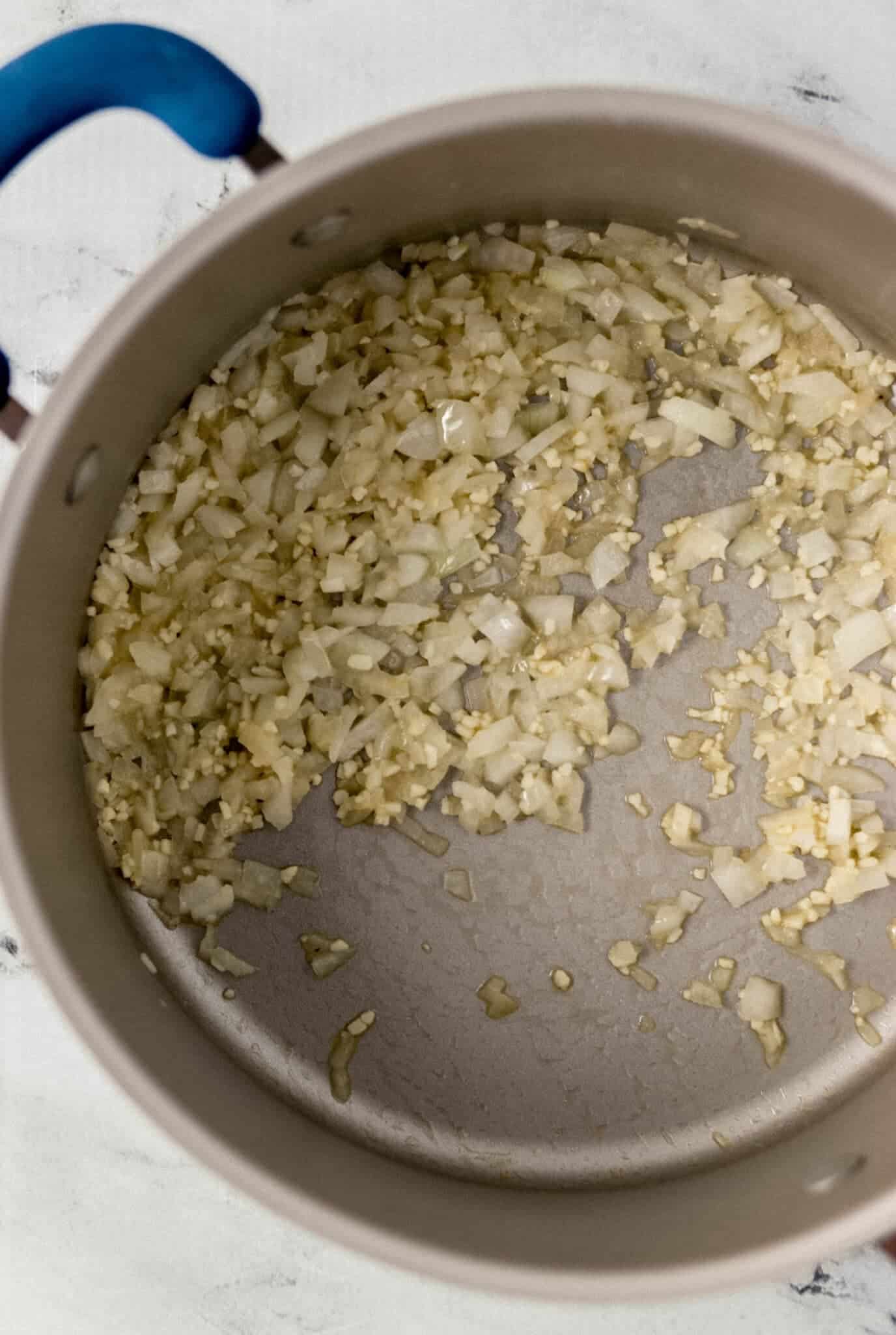 overhead view of melted butter, onion, and garlic combined in large pot