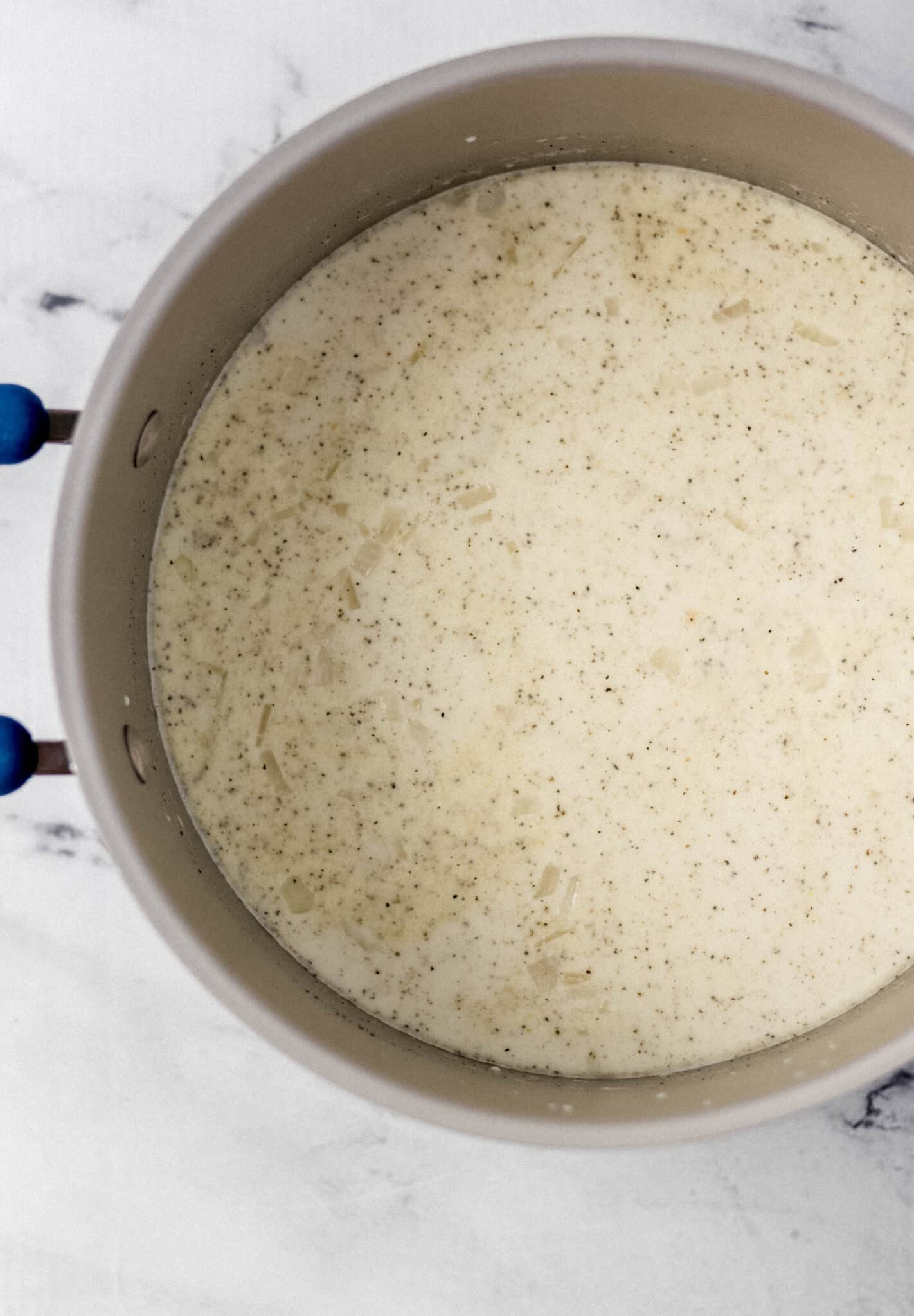 overhead view of chicken broth, heavy cream, and pasta added to large pot with the other ingredients