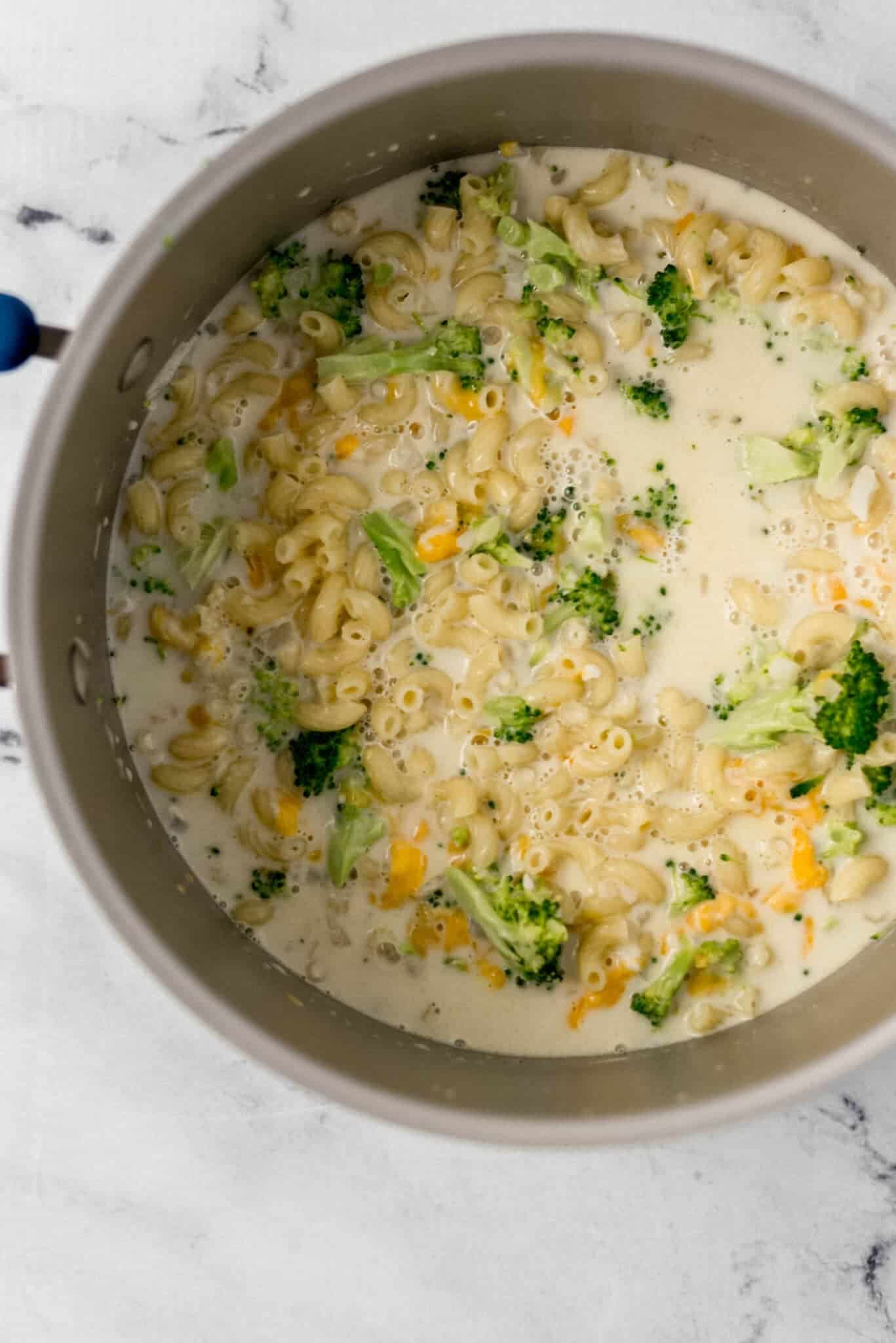 parmesan and cheddar added to large pot with other pasta ingredients in it