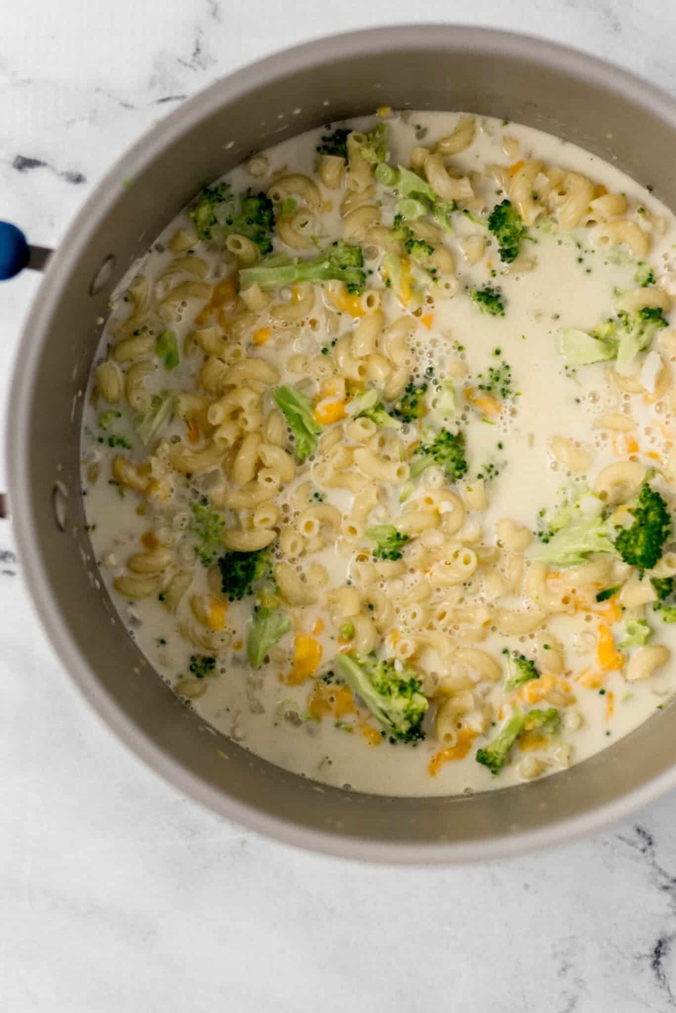 parmesan and cheddar added to large pot with other pasta ingredients in it 