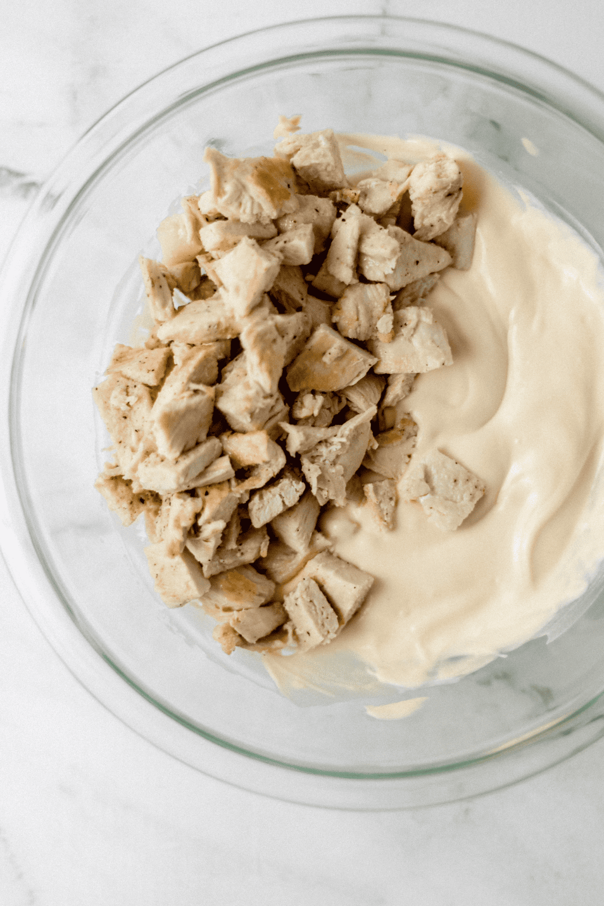 chicken and mayo mixture in glass mixing bowl 