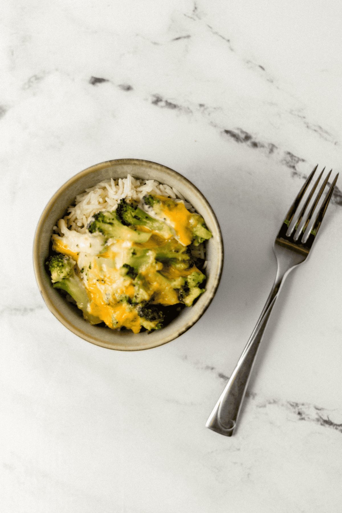 single serving of finished bake in bowl with rice beside a fork on marble surface