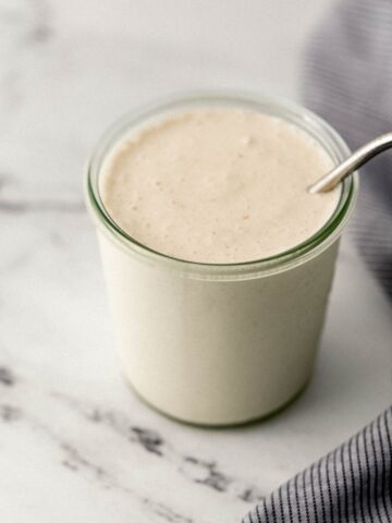 close up side view of milkshake in glass with straw in it beside cloth napkin