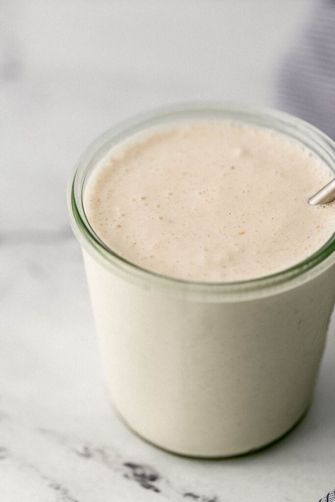 close up side view of milkshake in glass with straw