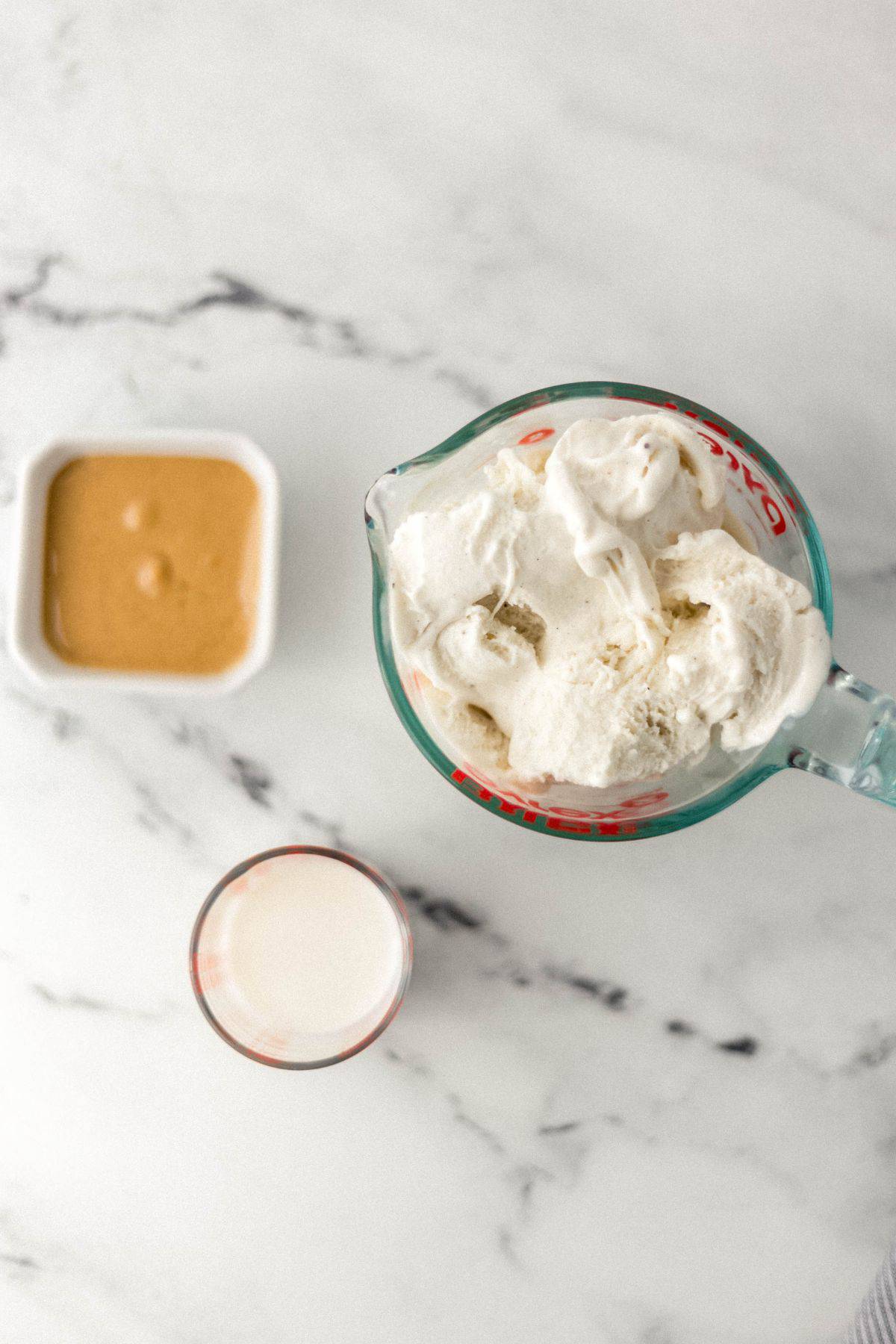 overhead view of ingredients needed to make milkshake in separate containers on marble surface 