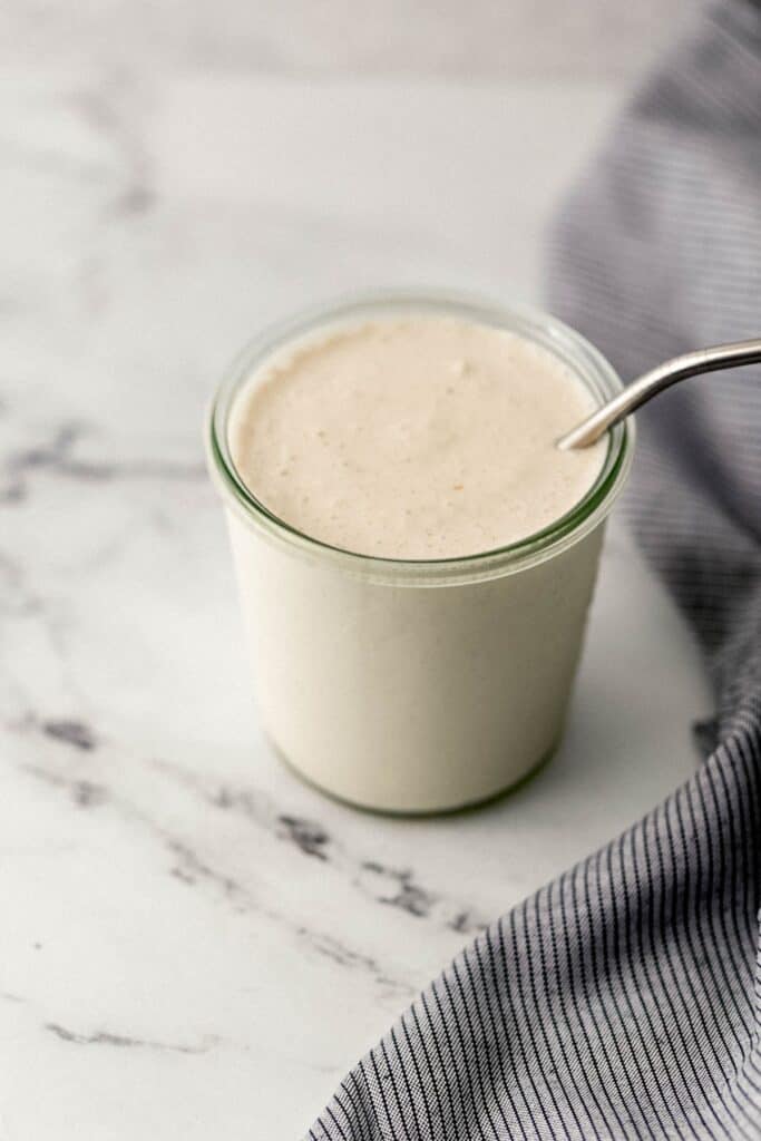 close up side view of milkshake in glass with straw in it beside cloth napkin