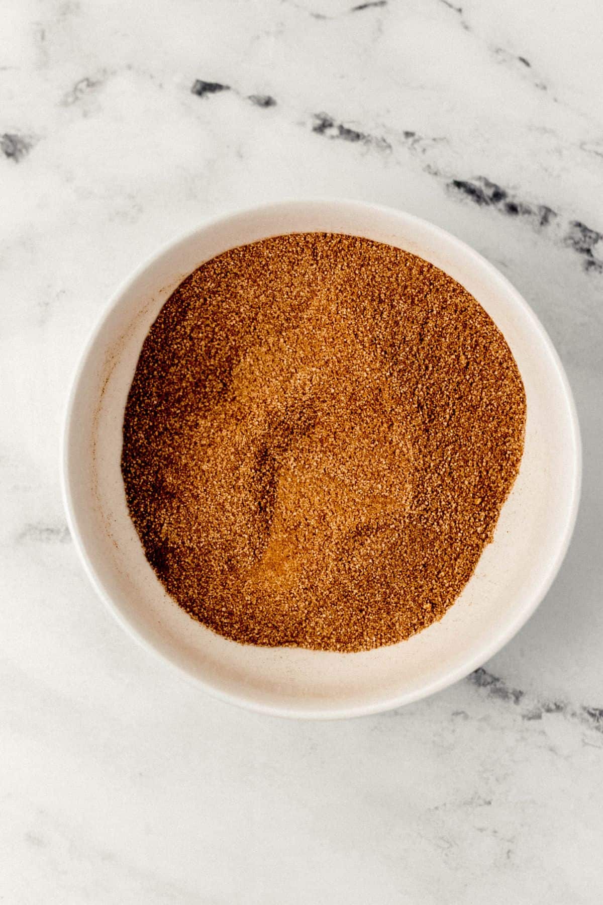 cinnamon sugar mixture in white bowl on marble surface 