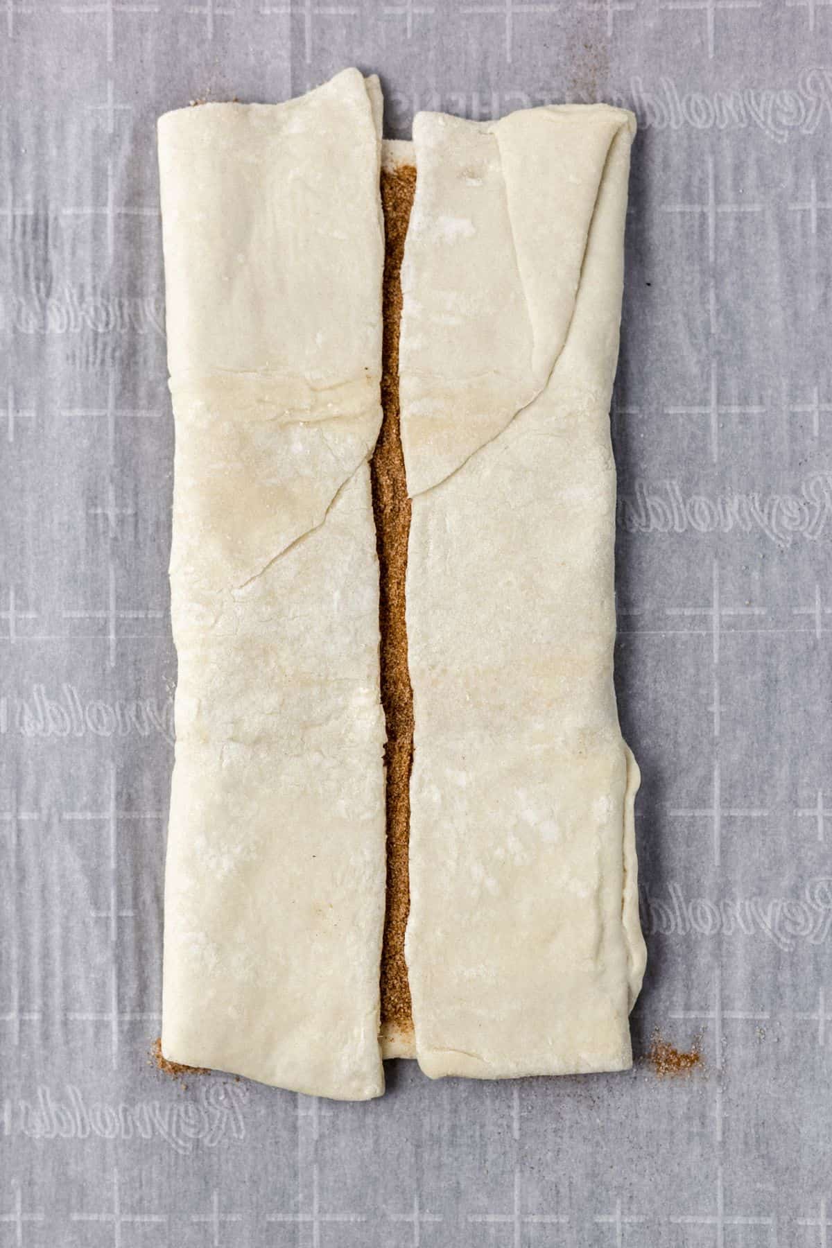 pastry with cinnamon sugar mixture folded on parchment lined baking sheet