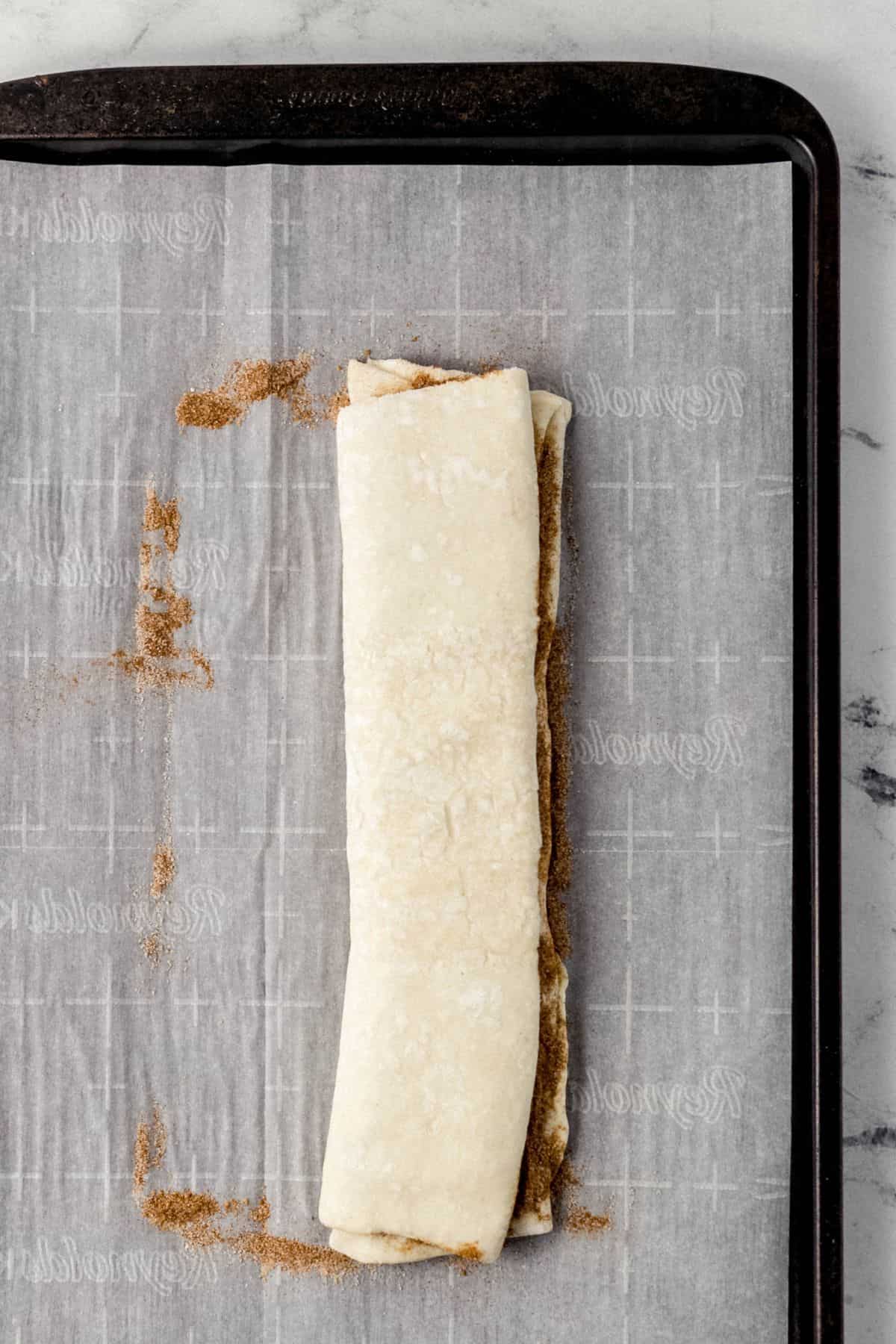 puff pastry dough folded in half on parchment lined baking sheet 