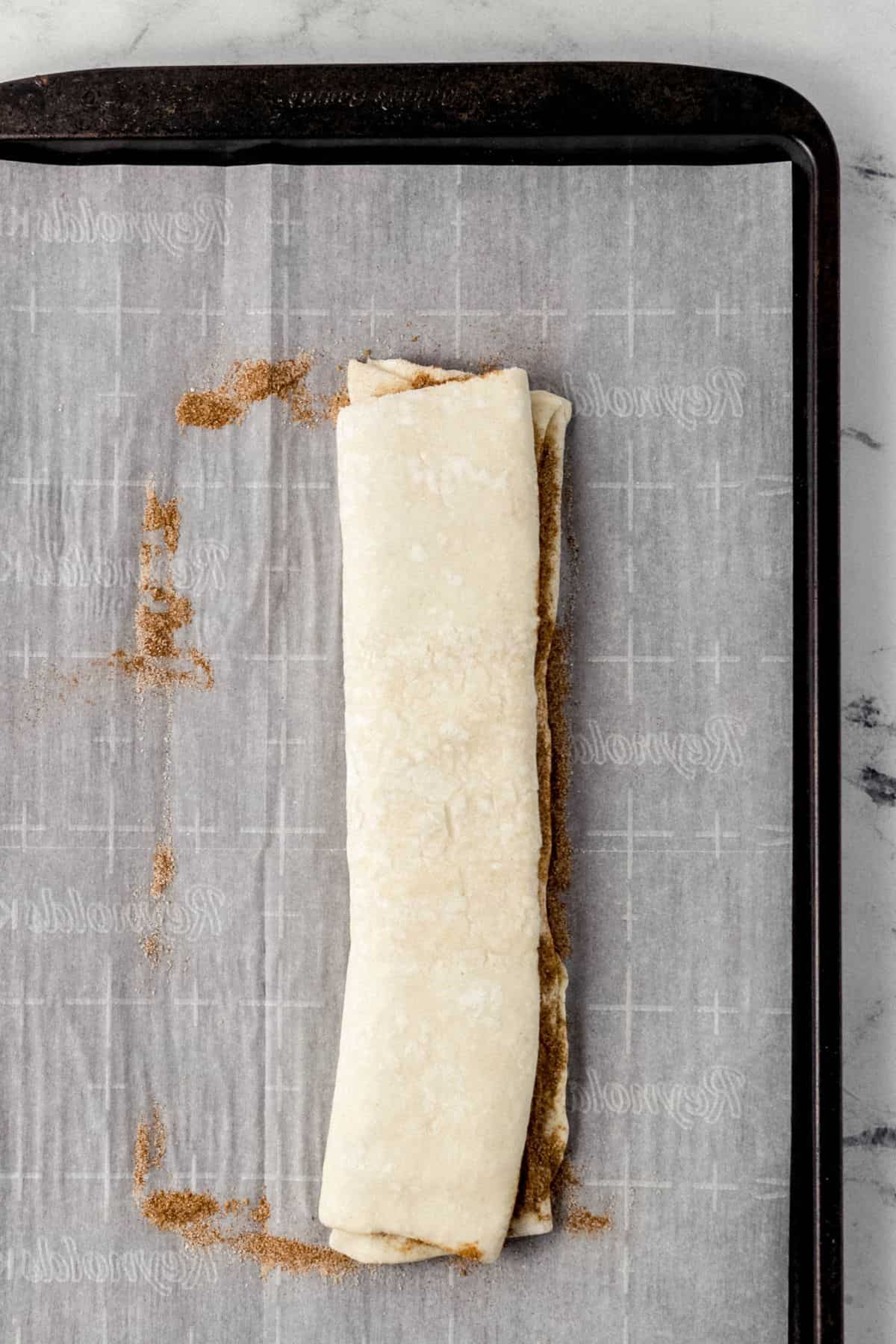 puff pastry dough folded in half on parchment lined baking sheet
