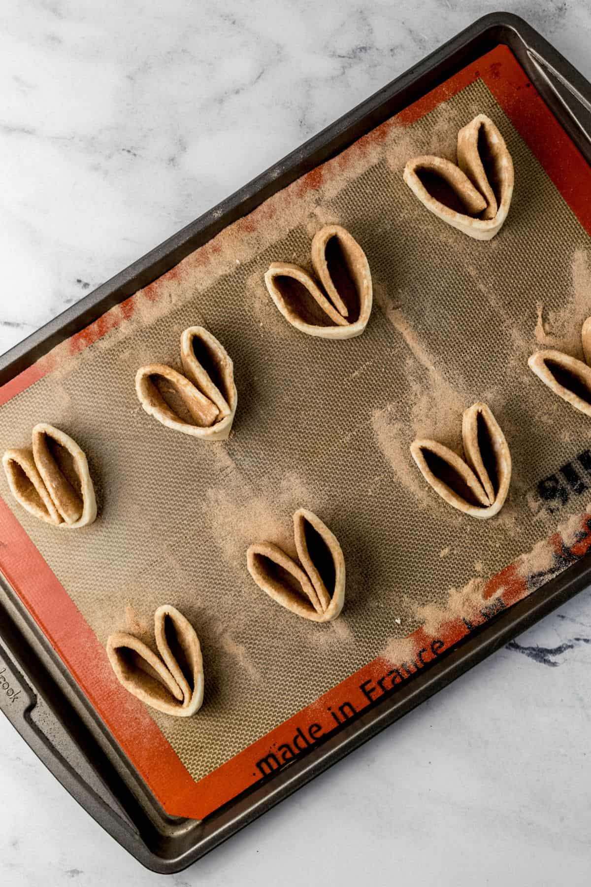 puff pastry cut to form individual elephant ears on baking sheet before baking