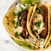 Close up view of jerk tacos in large white bowl.