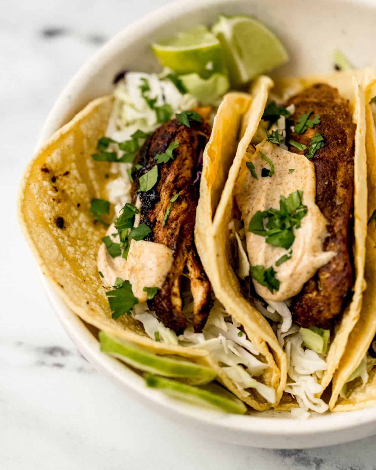 jerk chicken tacos simply lakita 4 Close up view of tacos in white bowl on marble surface.