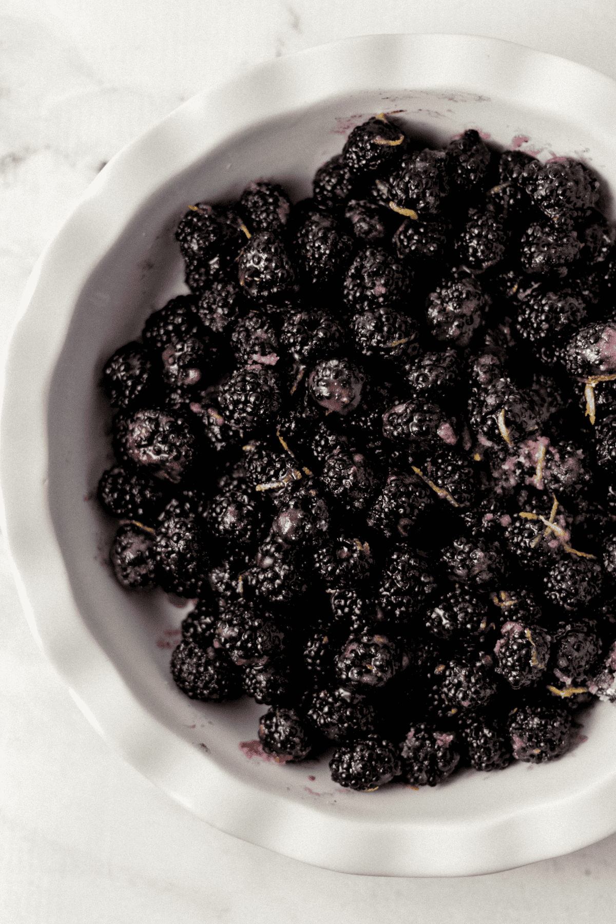 blackberry cobbler filling added to large white pie pan