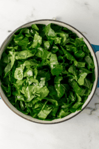 Freshly prepared greens added to a Dutch oven with the other ingredients.